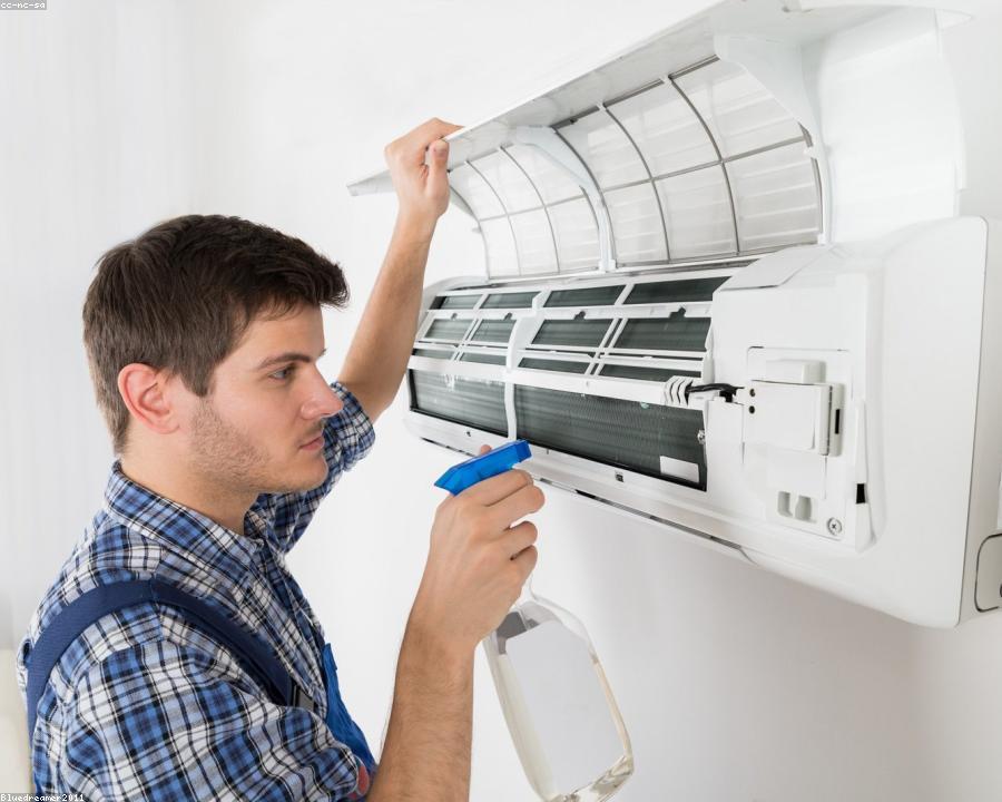 CoolFix technician servicing a wall-mounted split AC in a Lekki living room