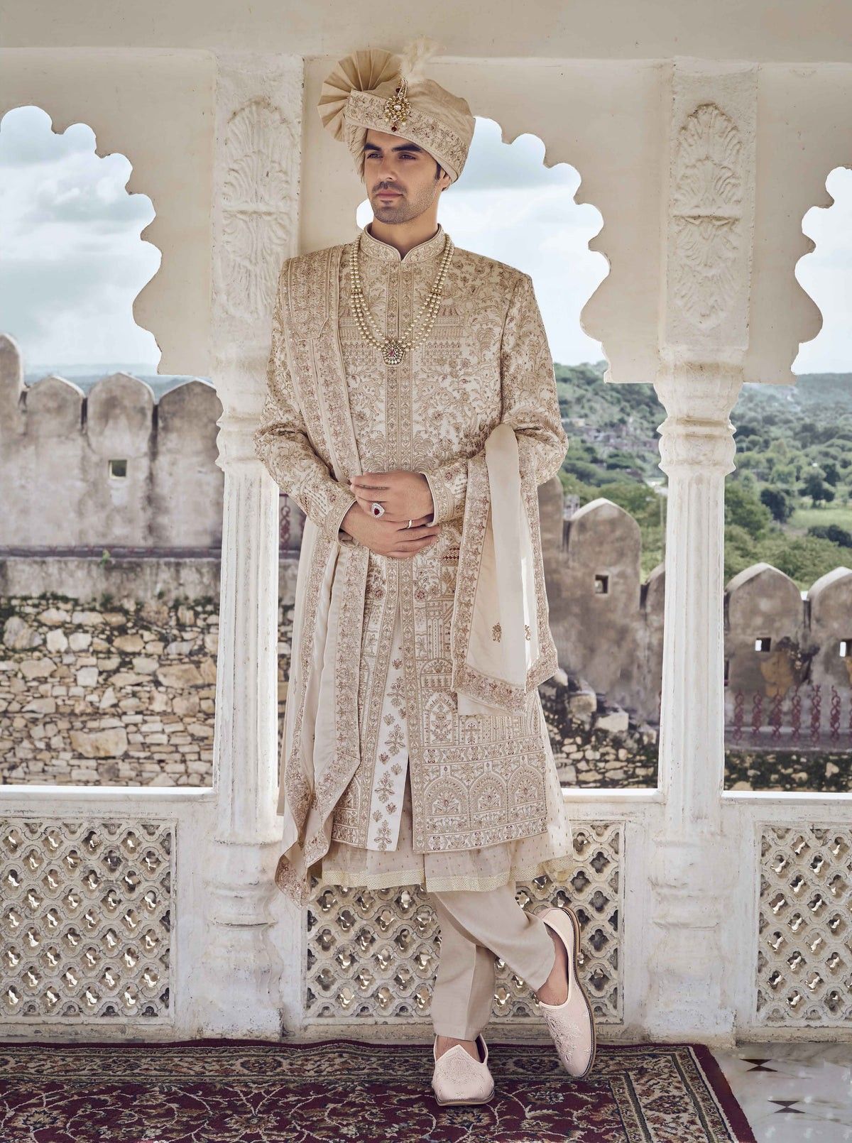 Groom in an ivory sherwani with a matching stole and brooch